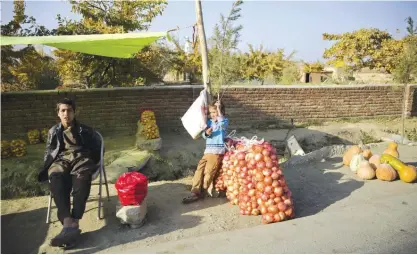  ??  ?? KABUL: Afghan villagers wait for customers to sell their agricultur­e products on the outskirts of Bagram city, north of Kabul yesterday. —AP