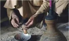  ??  ?? A Pakistani smoker putting hashish into a chillum pipe before smoking in Peshawar.