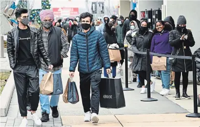  ?? NATHAN DENETTE THE CANADIAN PRESS ?? Masked customers line up at the Toronto Premium Outlets mall in Halton Hills on Black Friday for shopping sales.