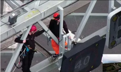  ?? Photograph: Essex Police/PA ?? A specialist police officer attempts to remove a Just Stop Oil protester from the gantry over junction 30 of the M25 on Wednesday.