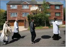  ?? (The New York Times/James Estrin) ?? Sunday marked the third procession of the Rev. Peter Purpura (second from left) through the Queens neighborho­od of Middle Village.