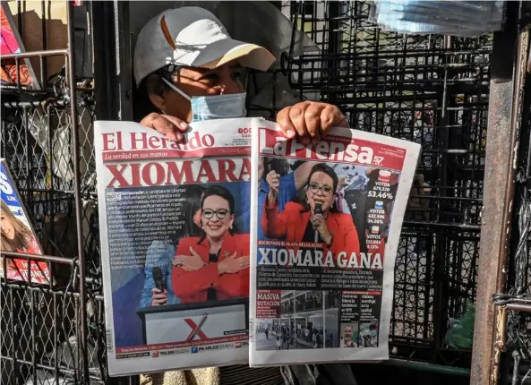  ?? AFP ?? Una vendedora sostiene las portadas de los periódicos que muestran la imagen de la candidata opositora de izquierda Xiomara Castro, en Tegucigalp­a, este lunes, un día después de las elecciones generales en Honduras.