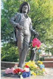  ?? PHOTO BY NATE BILLINGS, THE OKLAHOMAN ?? Flowers rest Sunday on the statue of James Garner on Main Street in downtown Norman. Garner died Saturday at age 86.