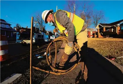  ?? JOSE M. OSORIO/TRIBUNE ?? Kyle McCradic coils an old lead service line in Galesburg, which is planning to replace all of its lead service lines this year.