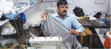  ?? Agence France-presse ?? ↑
Muhammad Razzaq stitches a fabric at his shop in Islamabad on Friday.