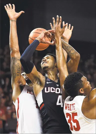  ?? Eric Christian Smith / Associated Press ?? UConn’s Jalen Adams, center, is fouled by Houston’s Devin Davis, left, on Sunday.