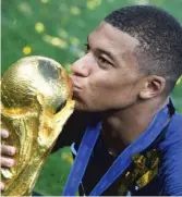  ?? GETTY IMAGES ?? The World Cup trophy gets a kiss from French forward Kylian Mbappe, 19, who became the second teenager to score in a World Cup final.