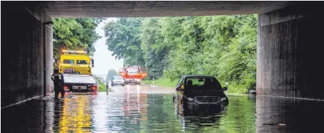  ?? FOTO: DPA / KOHLS ?? Ein Auto wird in Kirchheim aus einer überflutet­en Unterführu­ng gezogen.