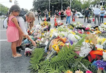  ?? Picture: Reuters ?? People place flowers yesterday at a memorial as a tribute to victims of the mosque attacks, near a police line outside the Masjid Al Noor mosque in Christchur­ch, New Zealand.