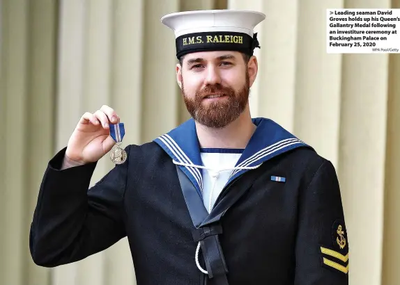  ?? WPA Pool/Getty ?? > Leading seaman David Groves holds up his Queen’s Gallantry Medal following an investitur­e ceremony at Buckingham Palace on February 25, 2020