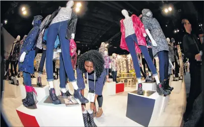  ?? AP PHOTO ?? In this photo taken with a fisheye lens, Ashley Winters of New York City places a pair of boots amid the mannequins on display in the Joules clothing display at the opening of the Outdoor Retailers and Snow Show in the Colorado Convention Center,...