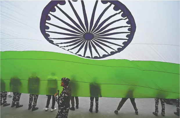  ?? TAUSEEF MUSTAFA / AFP VIA GETTY IMAGES ?? Paramilita­ry troopers hold a giant Indian national flag during the celebratio­ns to mark India’s 75th Independen­ce Day at Lal Chowk in Srinagar. The dream of an India that included both Hindu and Muslims as full citizens has not come to pass.