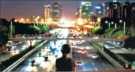  ?? AFP ?? ■
A woman looks out at a highway from a bridge in Beijing.