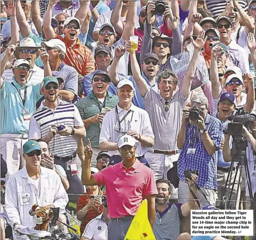  ?? AP ?? Massive galleries follow Tiger Woods all day and they get to see 14-time major champ chip in for an eagle on the second hole during practice Monday.