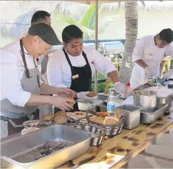  ??  ?? Nick Liu, left, cooks Canadian-style barbecue burgers at El Dorado Royale resort on Mexico’s Mayan Riveria. He’s part of an arrangemen­t that sees cooks from Canada demonstrat­e our cuisine to resort guests and culinary team.