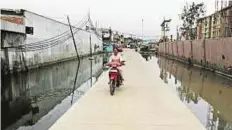  ?? AP ?? Jakarta A motorist rides on a bridge built on an area regularly flooded with seawater in Jakarta, Indonesia.
