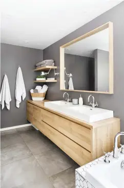  ??  ?? Spacieuse, lumineuse et dotée d'une alcôve pratique, cette double douche à l'italienne avec drain linéaire a de quoi faire rêver !
Le bois est un incontourn­able dans un décor qui se veut intemporel. Ici, le meuble-lavabo, les tablettes et le miroir sont mis en valeur par le mur gris chaud.