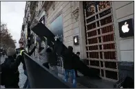  ?? AP/CHRISTOPHE ENA ?? Workers remove wooden planks from shop windows on the Champs-Elysees avenue in Paris on Sunday as stores reopened after Saturday’s protests.