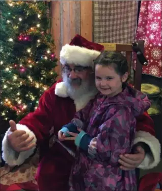  ?? BILL DEBUS — THE NEWS-HERALD ?? Santa Claus, portrayed by Paul Petras, greets Calie Walker of Newbury Township, and invites her brother and sister to join in the fun on Nov. 24 during Country Hearth Christmas at the Burton Log Cabin in Burton Village.