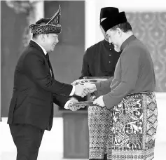  ??  ?? Yang di-Pertuan Agong Sultan Muhammad V (right), awarding the letter of appointmen­t to Internatio­nal Trade and Industry Minister Ignatius Darell Leiking at the Istana Negara in Kuala Lumpur. - Bernama photo