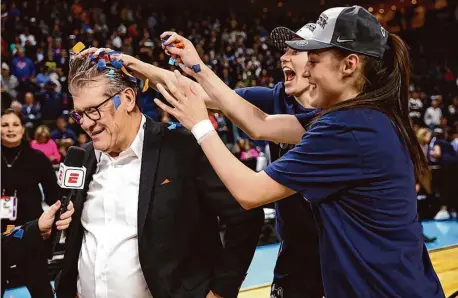  ?? Elsa/Getty Images ?? UConn players dump confetti on coach Geno Auriemma after defeating NC State 91-87 in double overtime in the NCAA regional finals at Total Mortgage Arena on March 28, 2022 in Bridgeport.