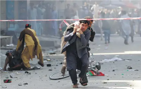  ?? Reuters, AFP ?? Above, a man carries a wounded person to hospital after a string of bombings in Jalalabad on Monday; left, a boy injured in the blasts receives treatment