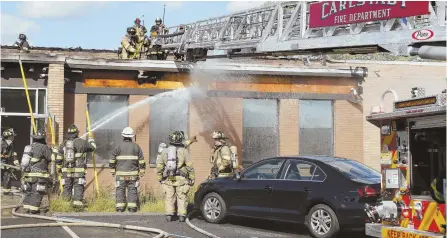  ?? AP PHOTOS ?? AFTERMATH: Firefighte­rs, above, hose down a building yesterday in Carlstadt, N.J., after a private jet crashed there, killing two crew members. No one else was aboard. The jet’s charred engine can be seen at right.