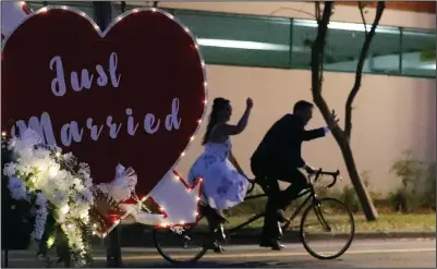  ?? (File Photo/AP/John Raoux) ?? Lane and Christine Abraben depart their drive-through wedding ceremony on a bicycle built for two May 14, 2020, after they were married at the Family and Civil courthouse in Gainesvill­e.