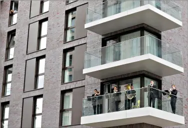  ?? (AP Photo/Kirsty Wiggleswor­th, File) ?? Musicians with the Royal Philharmon­ic Orchestra play from a balcony Sept. 5 at Wembley Park in London. It was the rchestra's first public appearance since the lockdown from the pandemic.