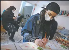  ??  ?? Bahareh Eskandarkh­an paints on a cloth bag at a Bavar workshop.