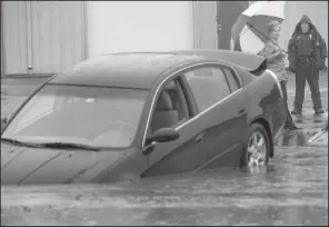  ?? Arkansas Democrat-Gazette/BENJAMIN KRAIN ?? A Little Rock police officer waits for a tow truck with the driver of a vehicle who drove into low area hidden by high water on Patterson and Hoffman roads during heavy rain Wednesday.