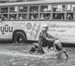  ??  ?? A man drives his motorcycle on a flooded street in Bangkok on Saturday. Overnight torrential rains flooded many slow to drain thoroughfa­res in the capital. AFP