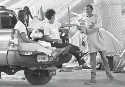  ?? LYNNE SLADKY/AP ?? Keturah Strickland, left, and Robin Lomax, center, of the Overtown Youth Center, deliver meals to the homeless during the coronaviru­s pandemic, May 14 in the Overtown neighborho­od of Miami. The center distribute­s lunch twice a week to those in need.