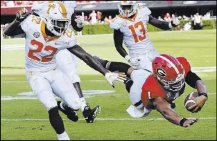  ?? Curtis Compton The Associated Press ?? Georgia quarterbac­k Justin Fields dives into the end zone past Tennessee safety Micah Abernathy to cap a 12-yard touchdown run in the third quarter of the Bulldogs’ 38-12 win Saturday.