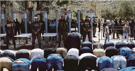  ?? AGENCY PIX ?? Muslims praying as Israeli border policemen stand outside the Lion’s Gate, a main entrance to the AlAqsa Mosque compound, in Jerusalem yesterday.
