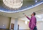  ?? BY ERIECH TAPIA, FOR THE OKLAHOMAN] [PHOTOS ?? Jesse Krewall, general manager for the Hilton Garden Inn, shows off the new chandelier in the main ballroom.