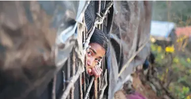  ?? MUNIR UZ ZAMAN / AFP / GETTY IMAGES ?? A Rohingya girl looks out from a shelter at a refugee camp in the Bangladesh district of Ukhia on Nov. 13.