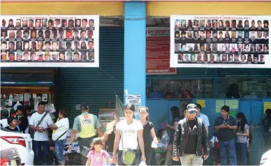  ??  ?? ENEMIES OF THE STATE – Pictures of suspected terrorists are posted in front of a business establishm­ent along San Pedro Street in Davao City. (Keith Bacongco)