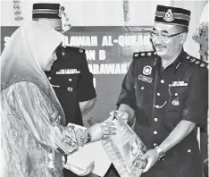  ??  ?? The sole participan­t in the Qariah category, Siti Norhapsoh from Meradong, receiving her prize from Kamal.