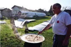  ??  ?? A man prepares food near the body, wings and tail of a SunAdria Holland Fokker-100 aircraft in the garden of a Croatian citizen.