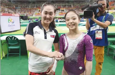  ?? The Associated Press ?? South Korean gymnast Lee Eun-ju, right, and her North Korean counterpar­t Hong Un Jong shake hands and smile for photograph­ers during the artistic gymnastics women’s qualificat­ion at the 2016 Summer Olympics in Rio de Janeiro, Brazil. Organizers of the...