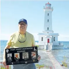  ?? KRIS DUBE/SPECIAL TO POSTMEDIA NEWS ?? Historian Rick Doan, president of the Point Abino Lighthouse Preservati­on Society, holds a plaque showing former keepers of the historic lighthouse on Lake Erie. Its 100-year anniversar­y will be celebrated all season, starting Saturday.