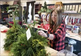  ?? BEN HASTY — READING EAGLE ?? Dee Ott, owner of the Geigertown Greenhouse, puts together a Christmas wreath in the retail shop. The Union Township business recently opened an expanded retail space.