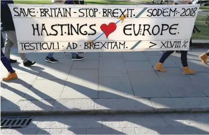  ?? — Reuters ?? Tourists walk past an anti-Brexit banner displayed opposite the Palace of Westminste­r in London on Thursday.