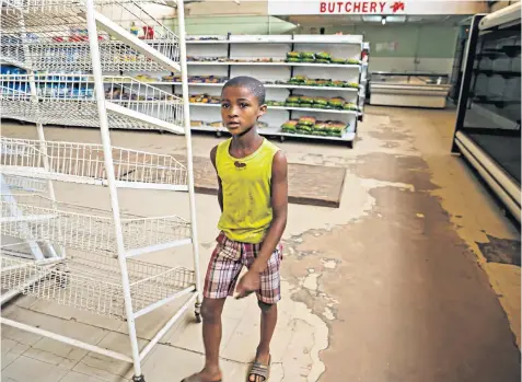  ??  ?? A young boy walks past empty shelves, including those for bread and meat products, in a grocery store in Harare, as Zimbabwe experience­s renewed shortages