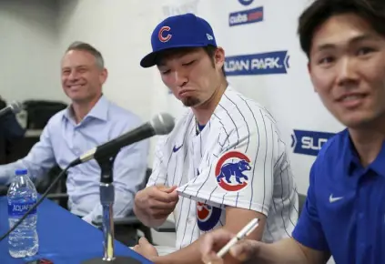  ?? Chris Sweda, Chicago Tribune ?? Cubs president of baseball operations Jed Hoyer, left, listens in as Seiya Suzuki speaks to media during an introducto­ry news conference last week in Mesa, Ariz.