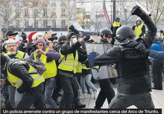  ??  ?? Un policía arremete contra un grupo de manifestan­tes cerca del Arco de Triunfo.