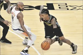  ?? ASSOCIATED PRESS ?? MEMPHIS GRIZZLIES GUARD JA MORANT (12) drives against Phoenix Suns guard Jevon Carter (4) in the first half of an NBA game on Monday in Memphis, Tenn.