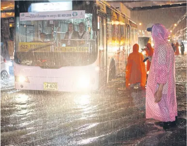  ?? PattaraPon­g ChatPattar­asill ?? City Hall officials in ponchos are on hand to help direct traffic along flooded Ngam Wong Wan Road near Pongpet intersecti­on during heavy rain on Wednesday night.