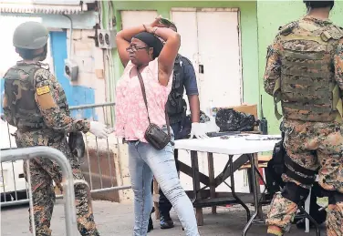  ?? PHOTO BY ADRIAN FRATER ?? A woman positions herself for a body search at a military checkpoint in Mount Salem, St James, the first declared zone of special operations, on Monday.